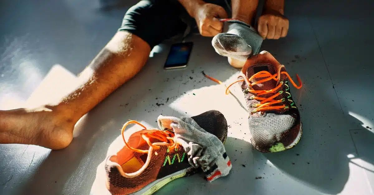Man sitting on the floor putting on running shoes and getting ready for a testosterone workout