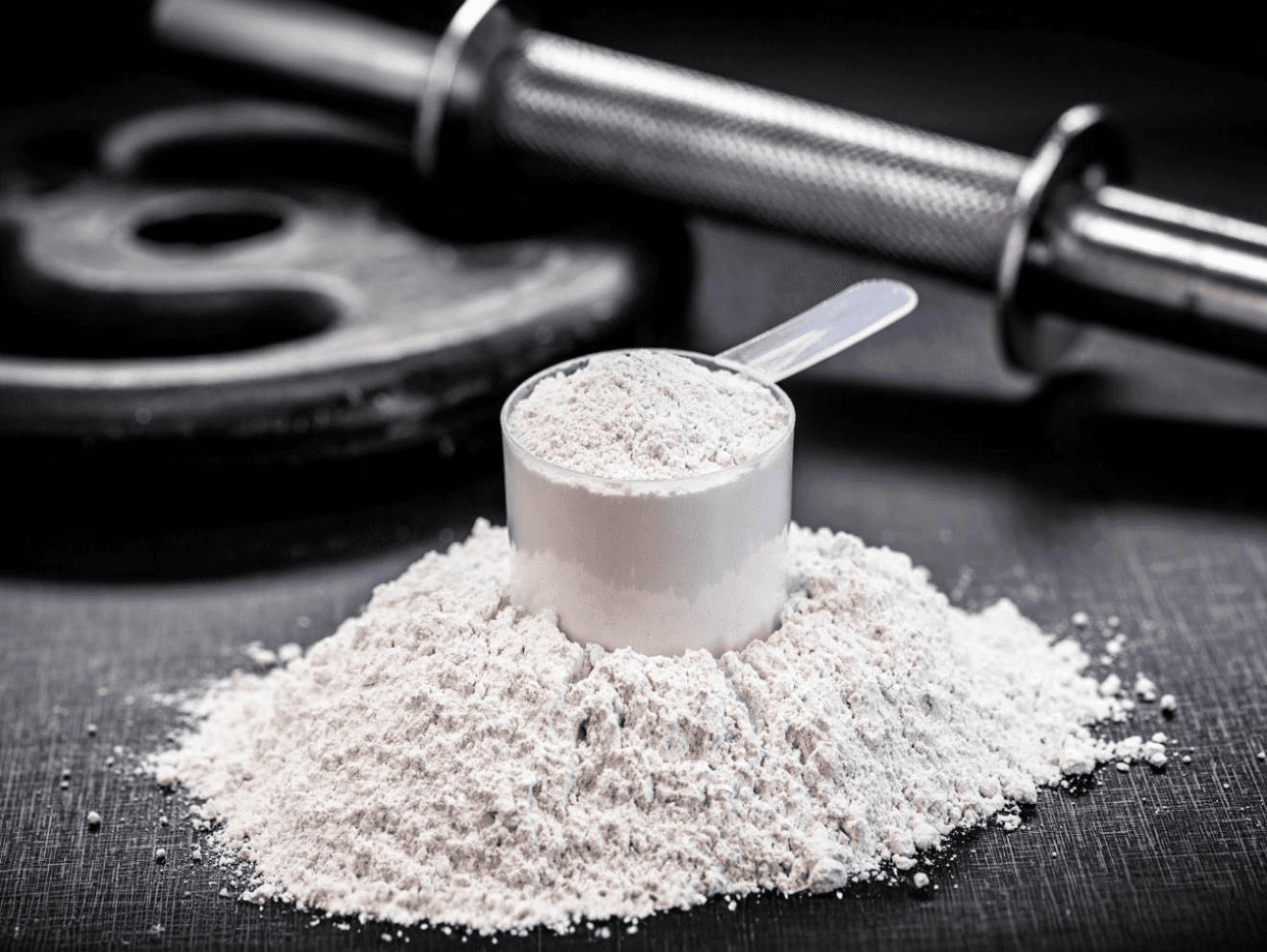 Kreatintilskud i pulverform ved siden af træningsvægte