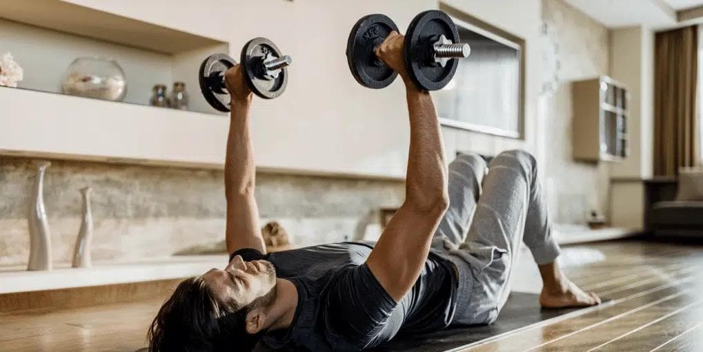 Man lying on the floor exercising by lifting dumbbells.