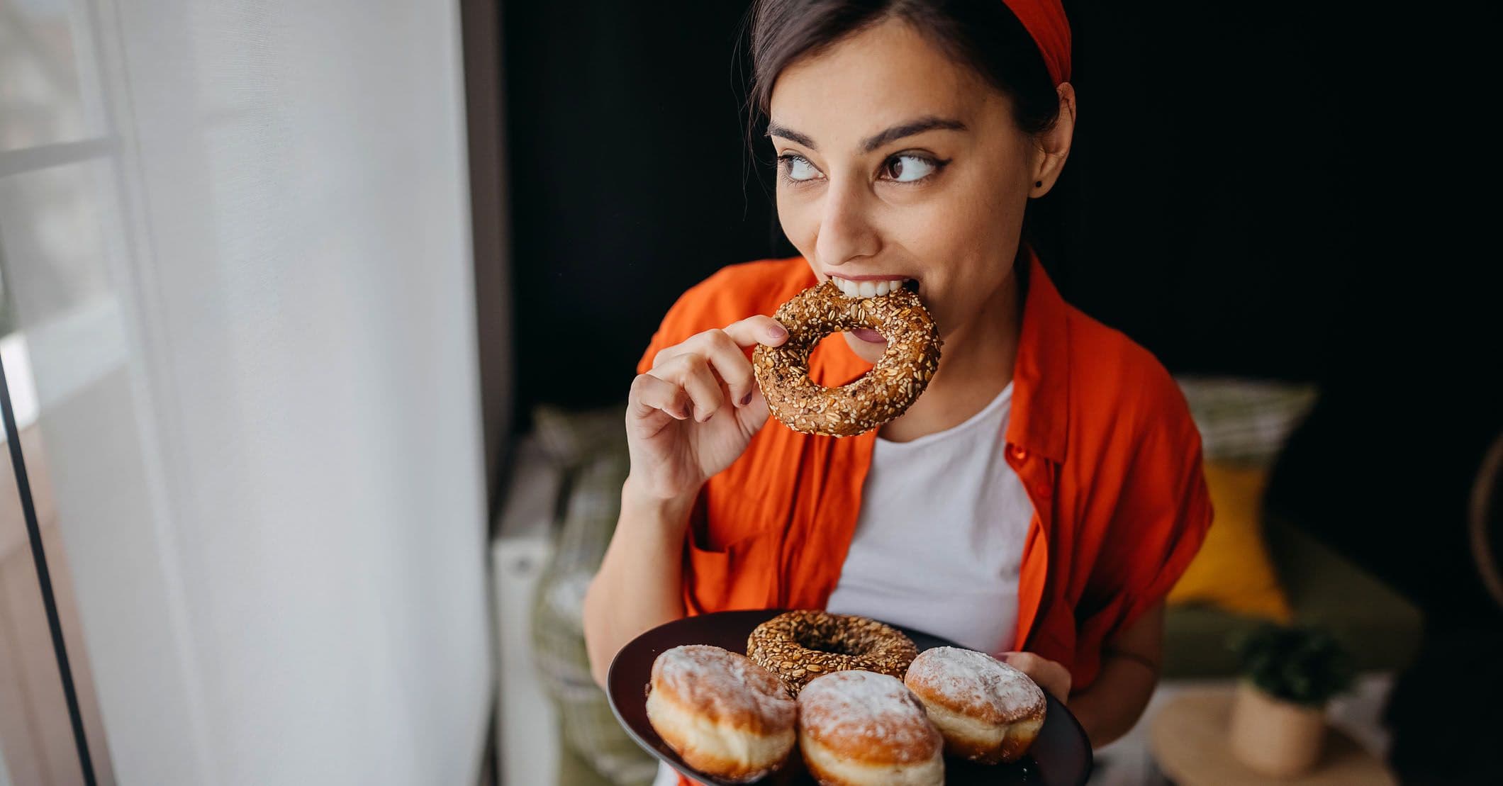 Ung kvinne spiser donuts og berlinerboller