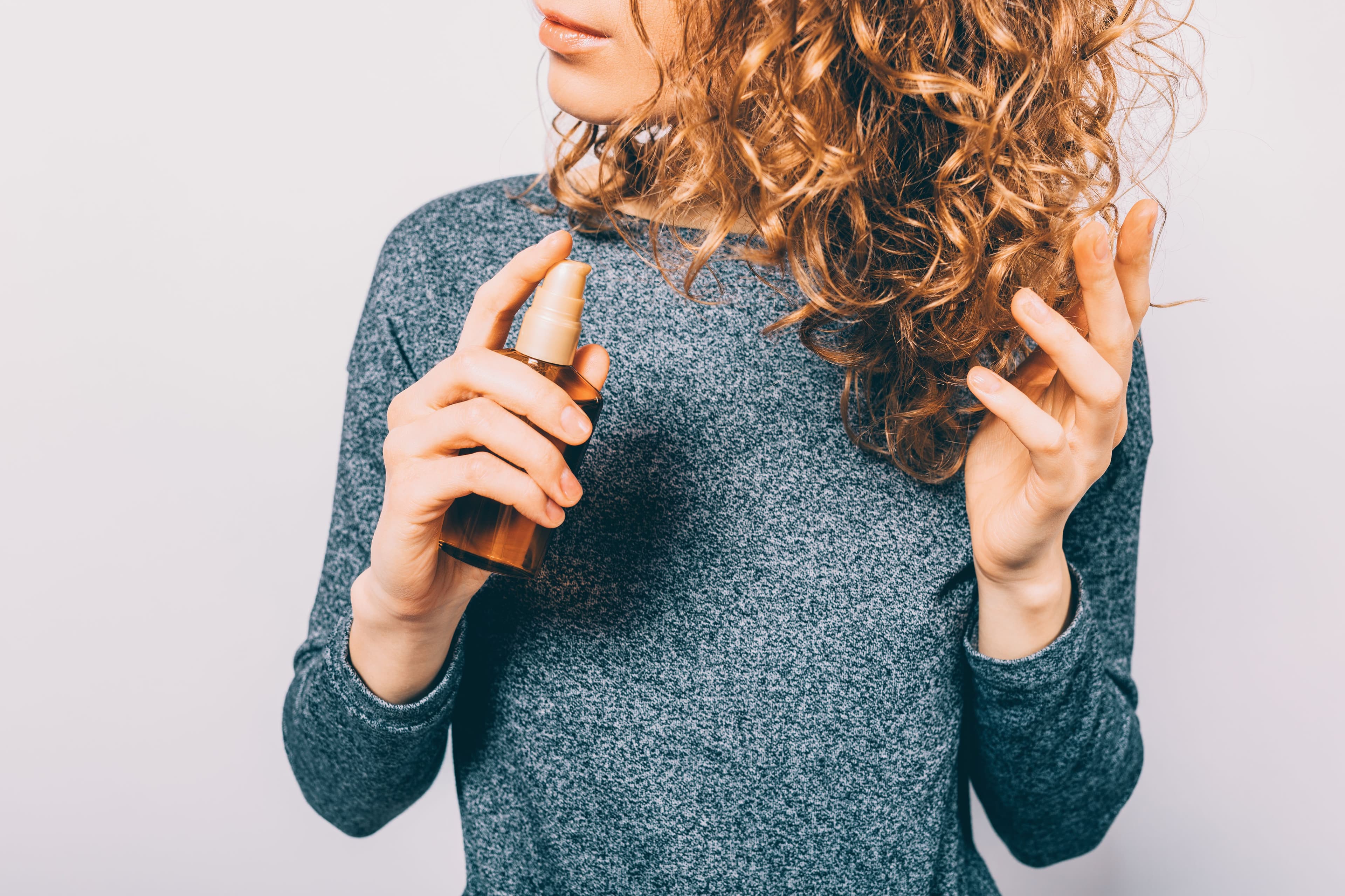 A woman uses a hair product to get thicker hair
