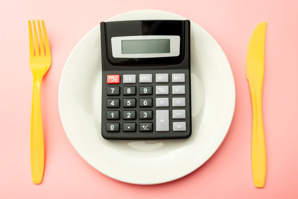 Calculator placed on a plate with a knife and fork next to it.