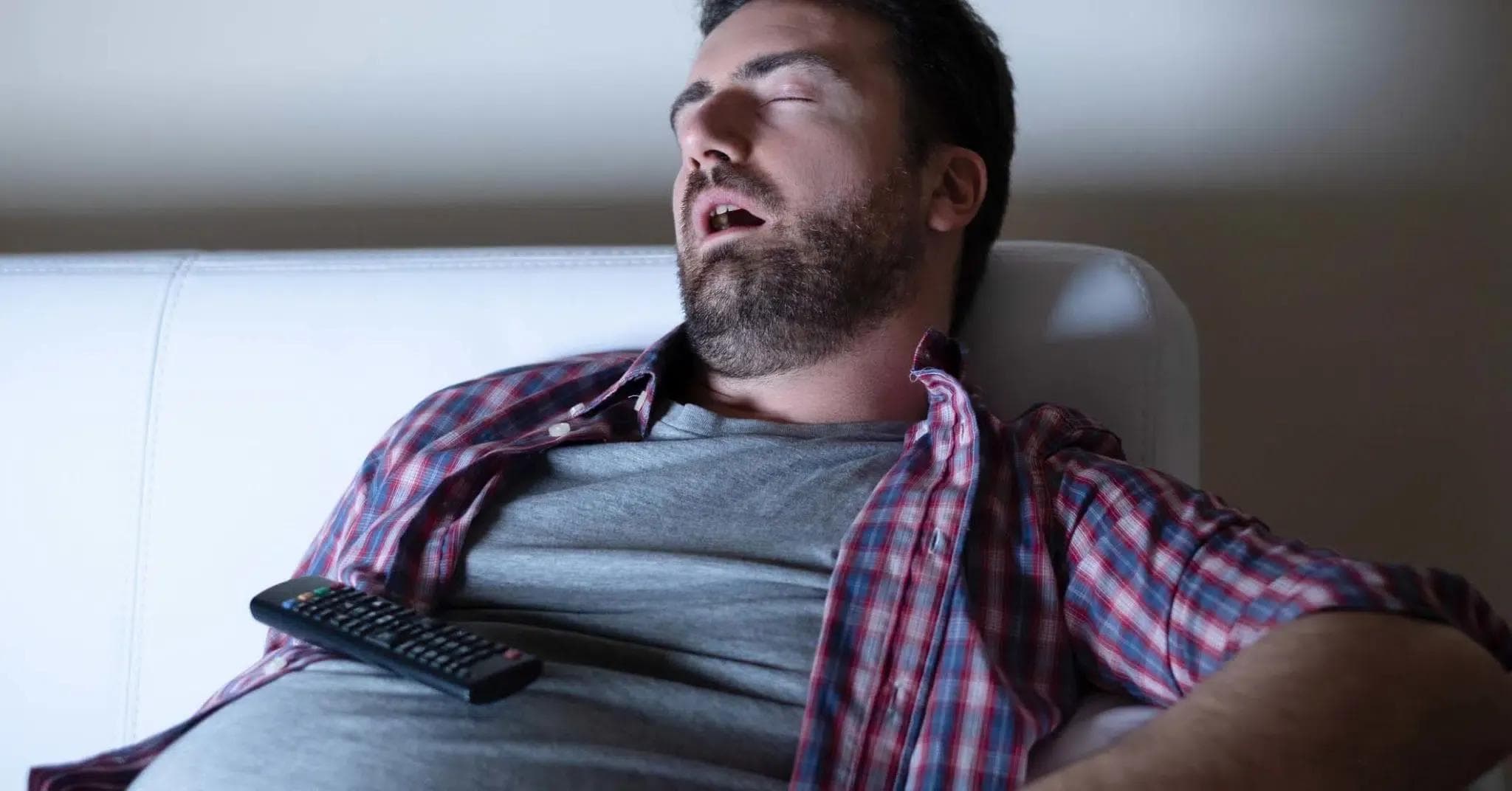 Man with no energy who has fallen asleep on the sofa in front of the TV