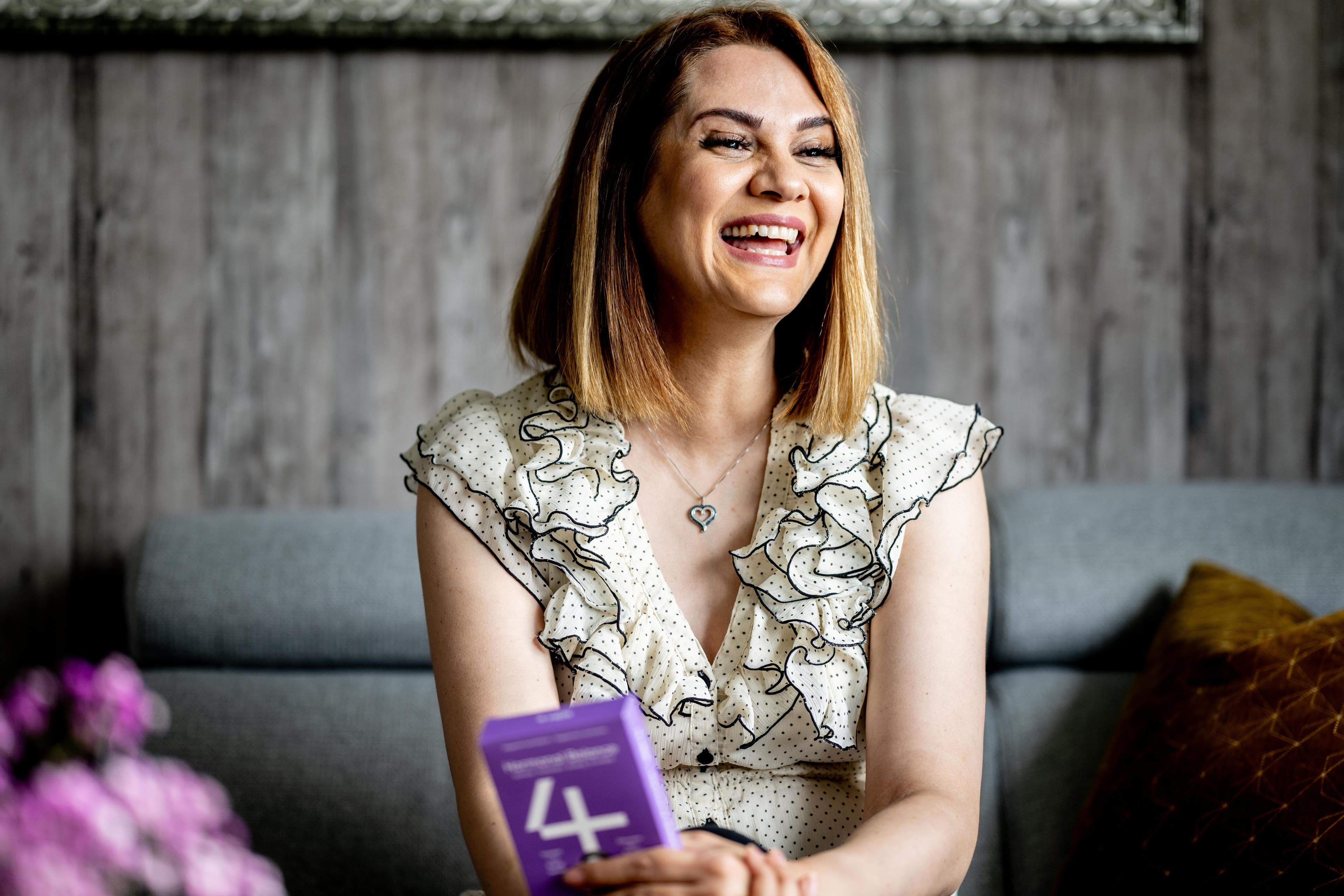 Mahsa: Leende kvinne holder en pakke med 4HER Hormonal Balance
