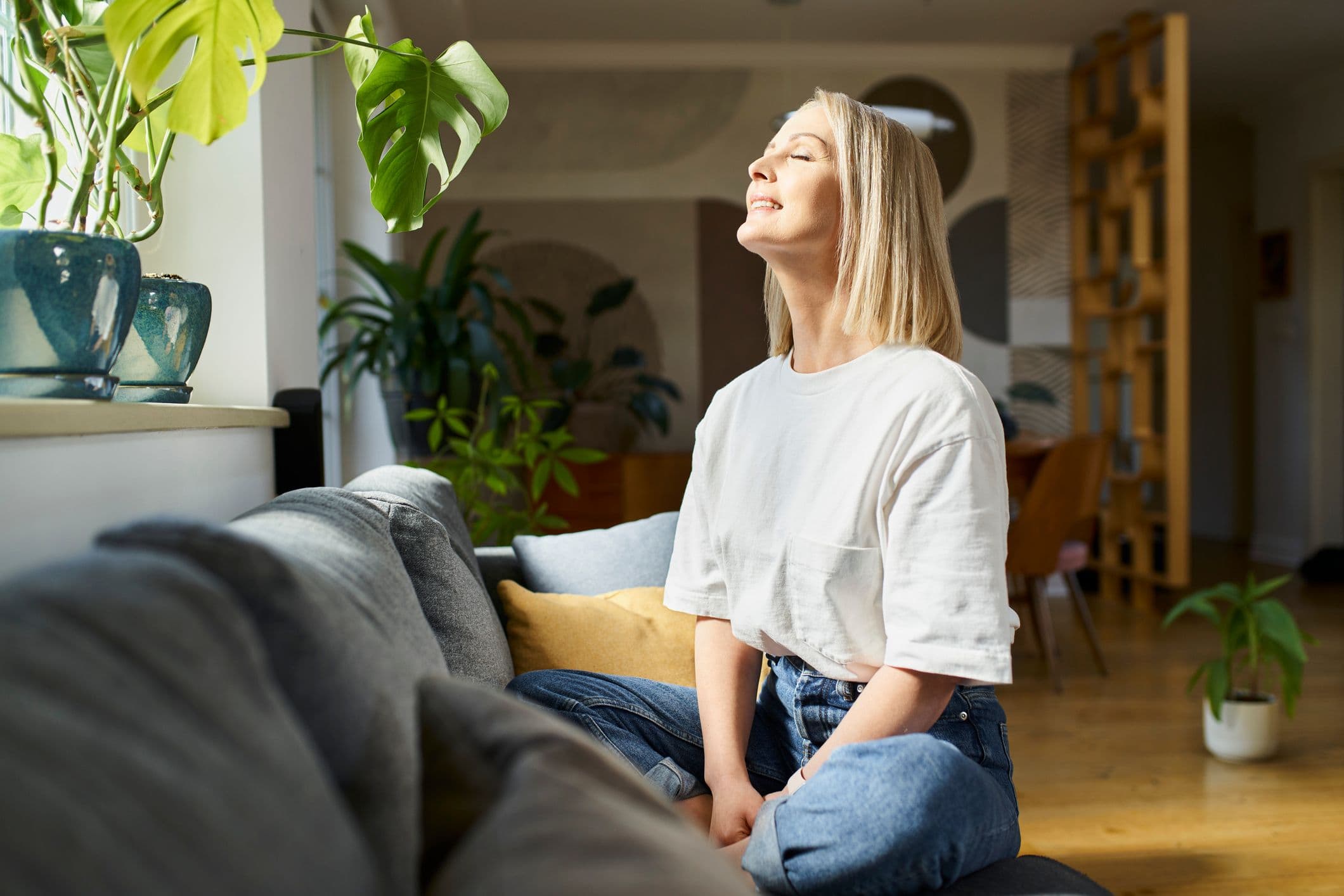 Avslappnad kvinna som sitter i en soffa – en symbol för fördelar magnesium kan ge, som lugn, återhämtning och välmående