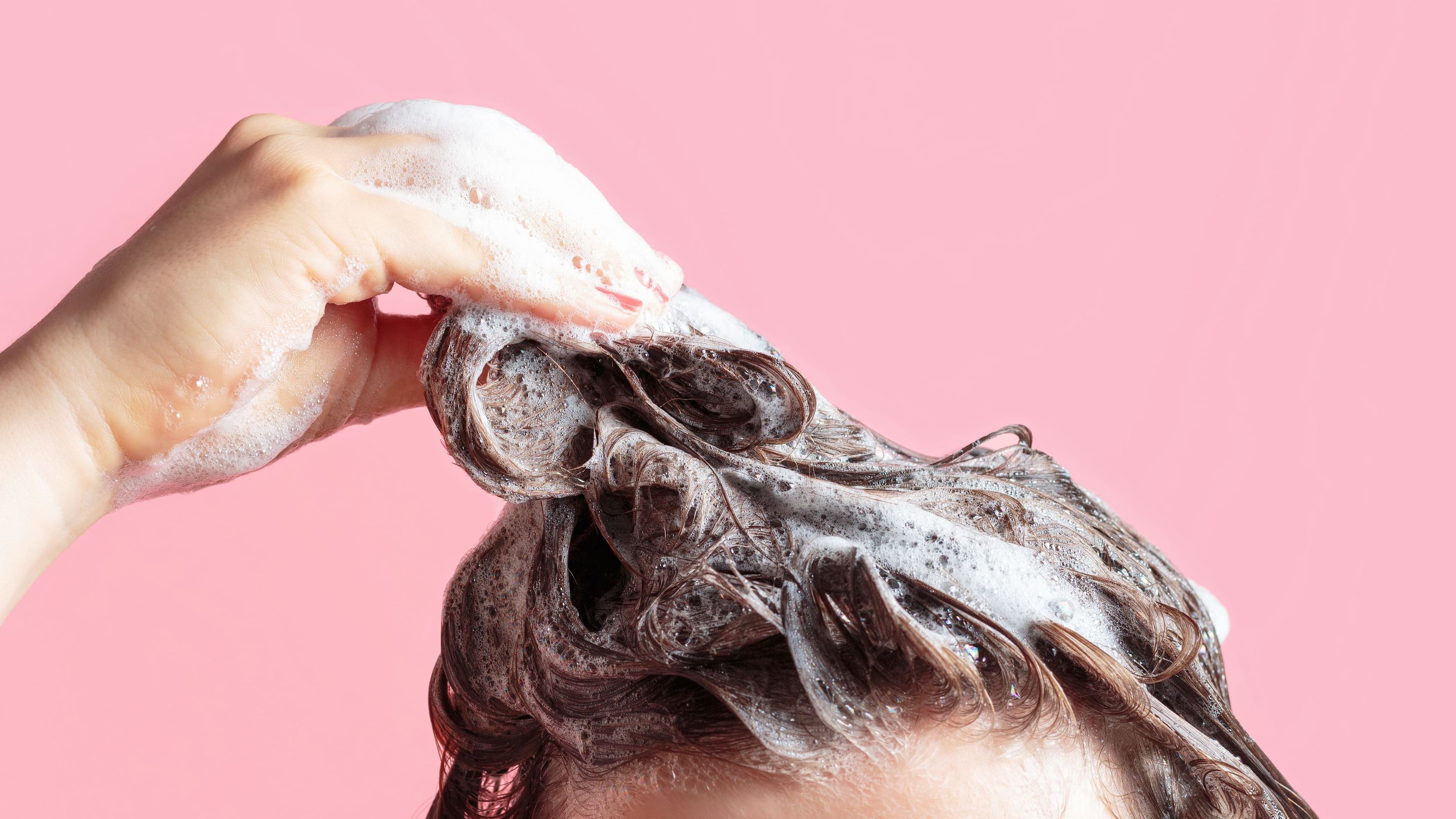 A woman washes her hair with a shampoo for volume