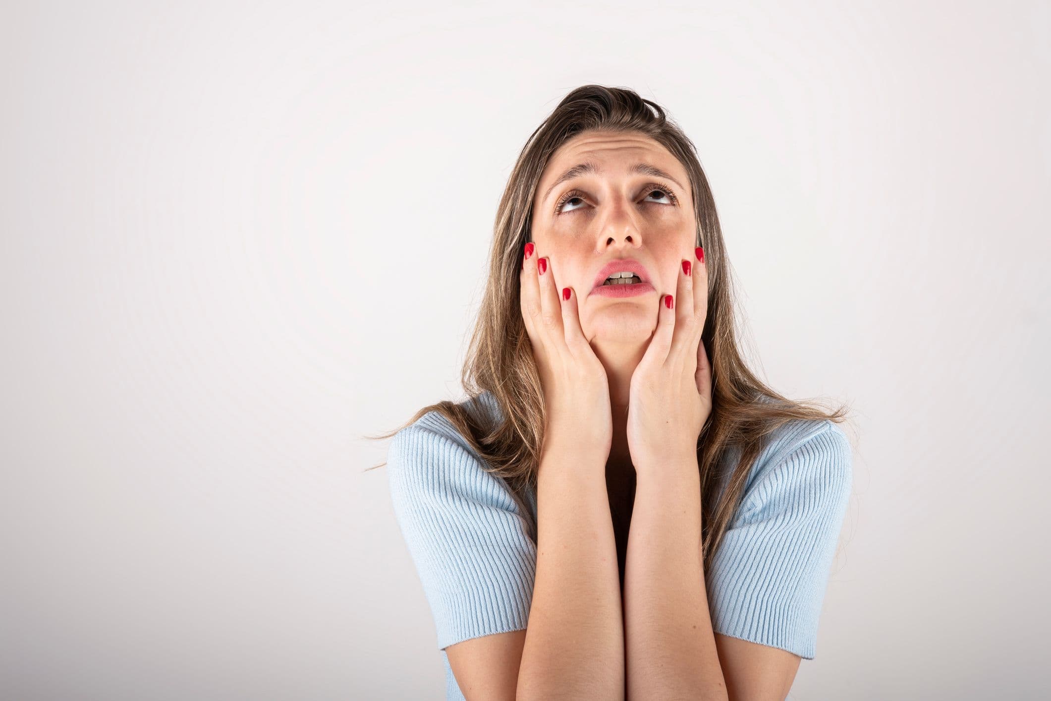 Stressaantunut nainen pitää käsiään kasvojensa edessä