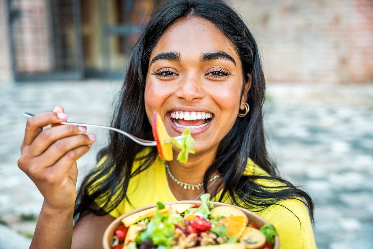 Glad kvinde, der spiser en salat