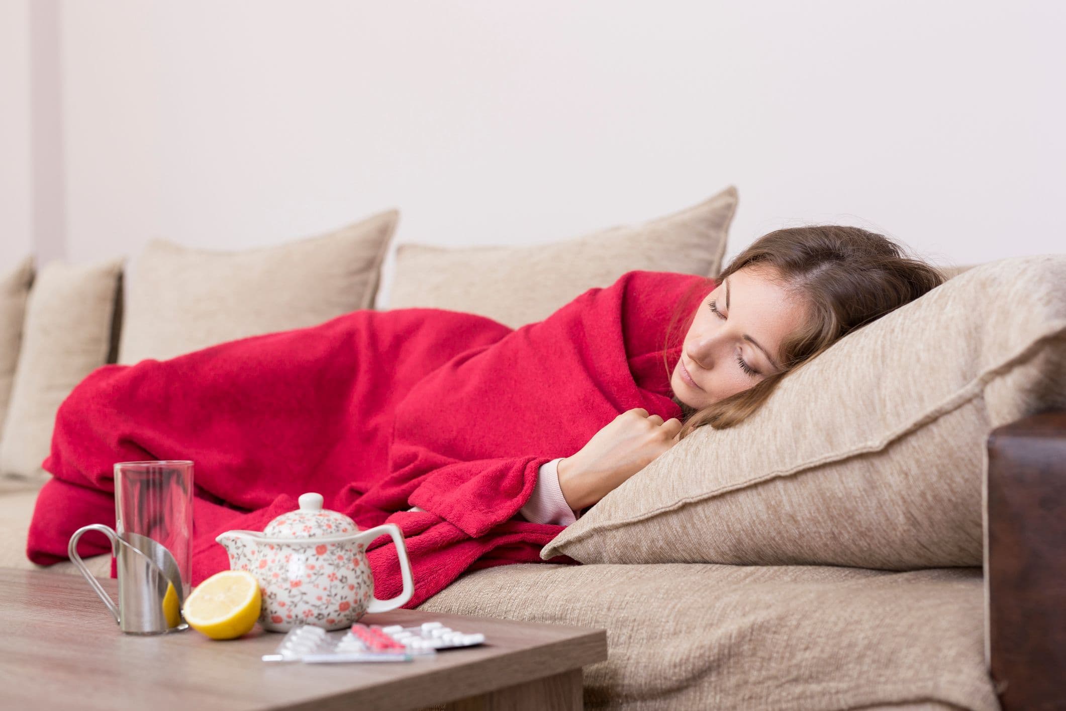 Flunssainen nainen lepää sitruunatee edessään