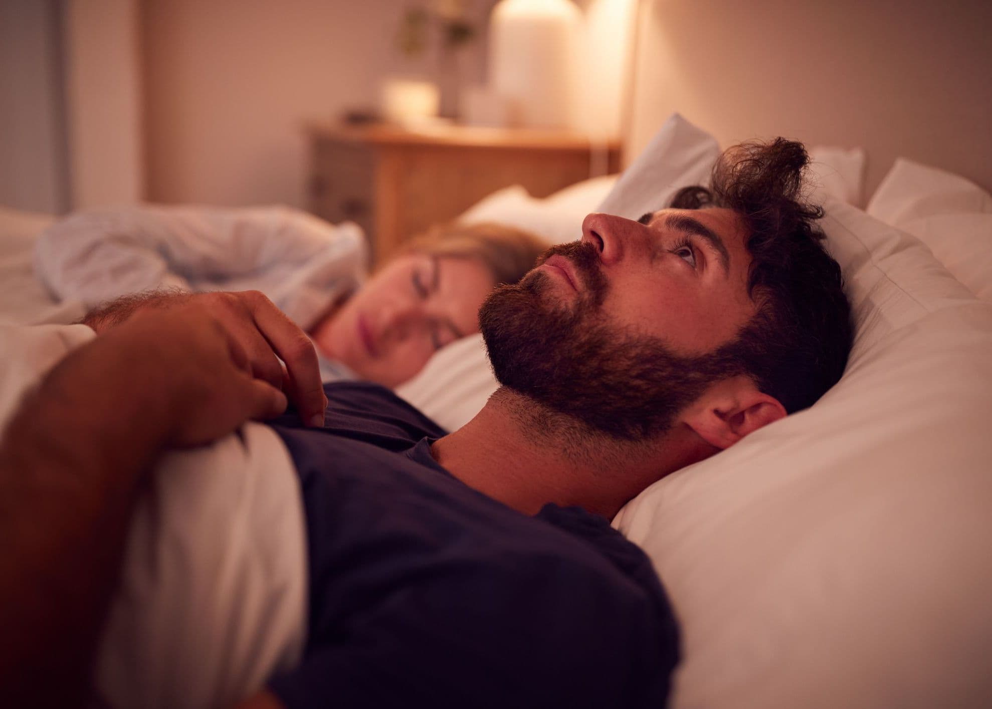 Sleepless man staring up at ceiling from bed