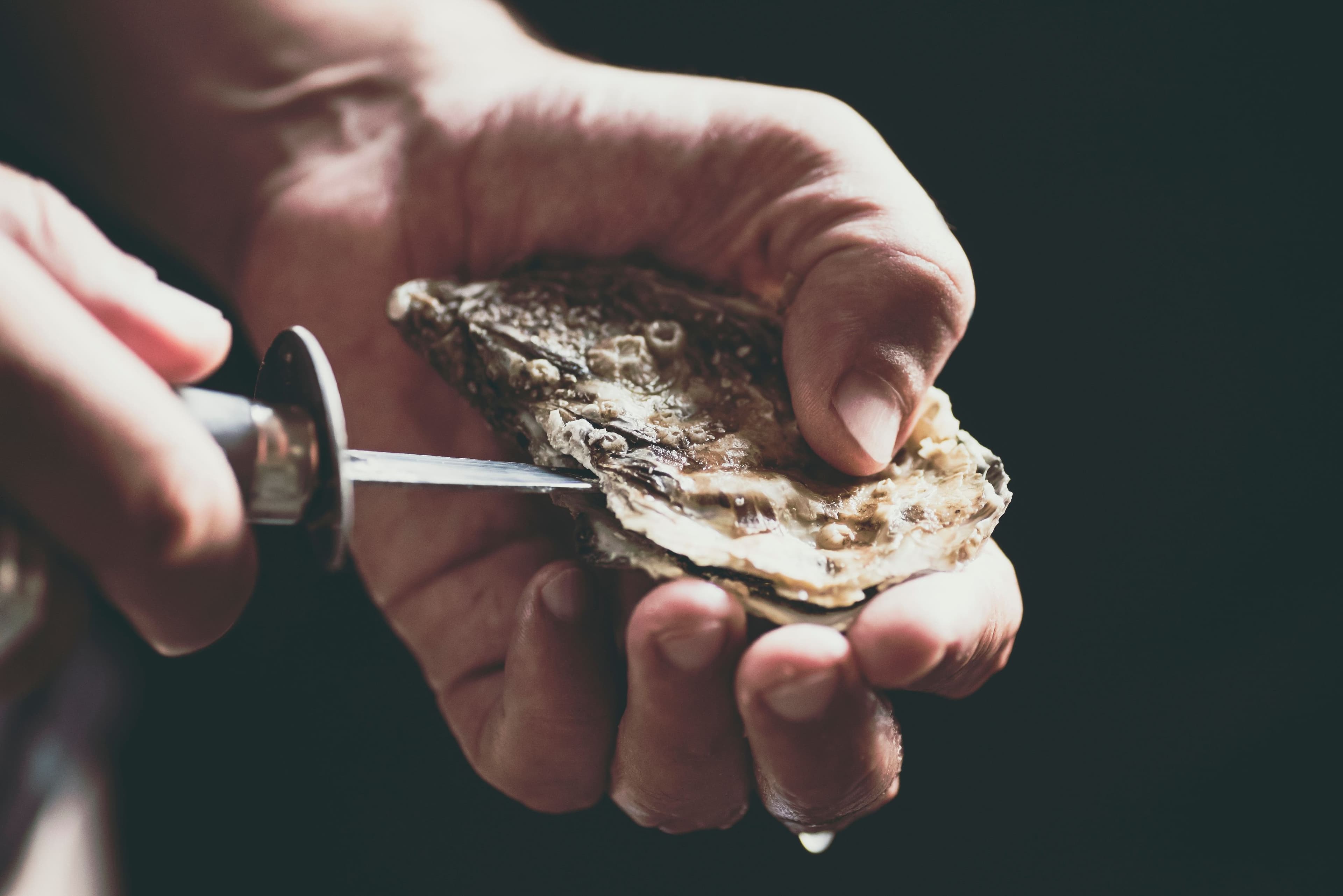 Man opening an oyster with a knife