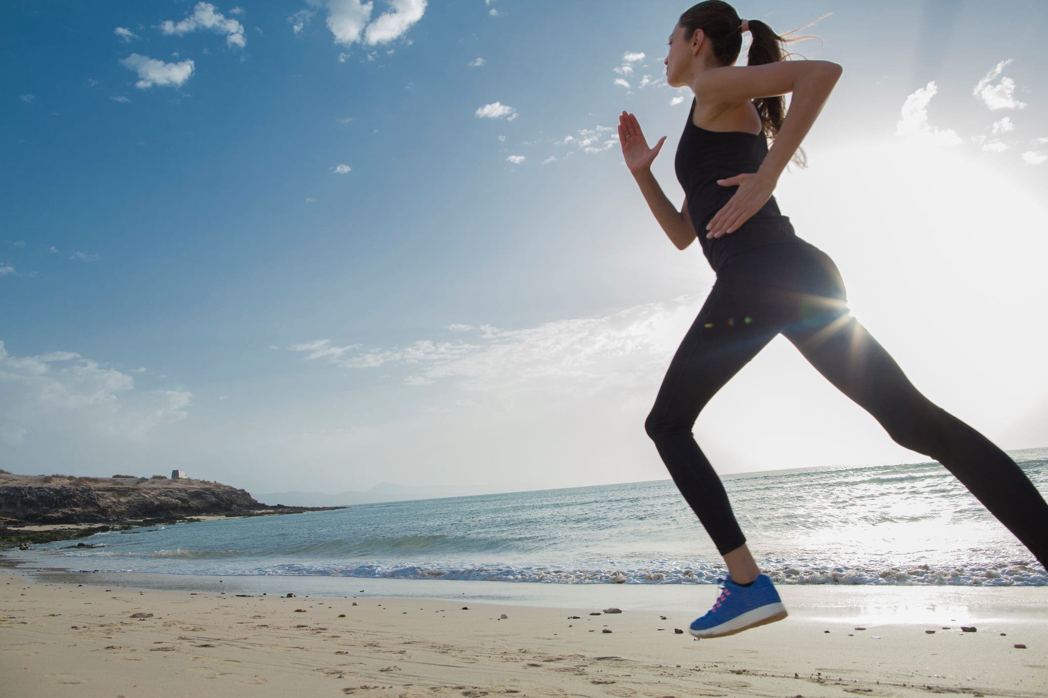 En kvinna som joggar på stranden.