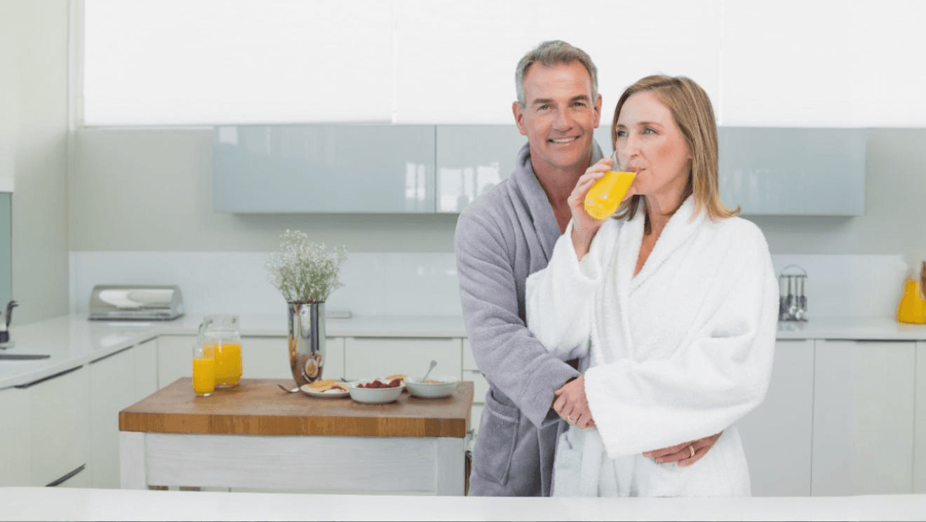 Par i köket med apelsinjuice som symboliserar en c vitamin boost och stöd för cellskydd mot oxidativ stress