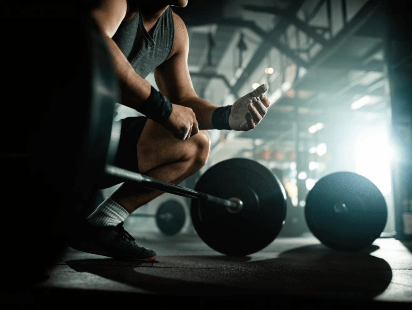 Mand i fitnesscentret, der forbereder sig til vægtløft