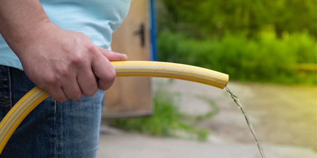 Man håller i en vattenslang med svagt vattenflöde - som symboliserar en svag urinstråle