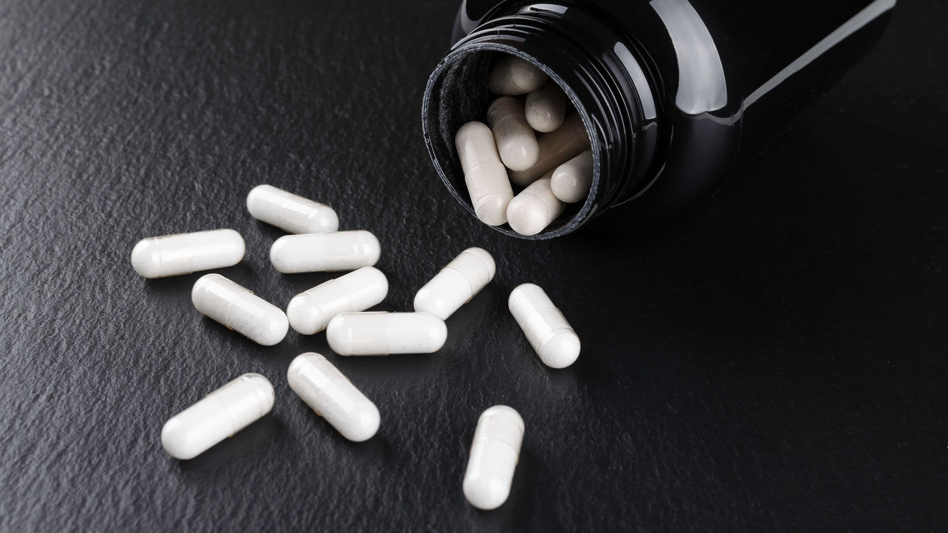 Öppen burk med ZMA-tillskott mot svart bakgrund – magnesium bra för muskler och återhämtning