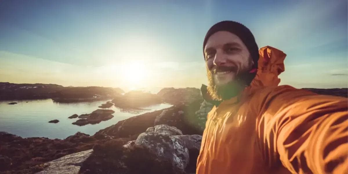 Man som ler och tar en selfie i naturen